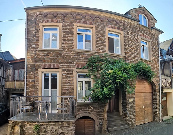 Historisches Bruchsteingebäude des Weinguts Friderichs in Ediger-Eller an der Mosel, mit Balkon, begrüntem Hausportal und großem Holztor im alten Weindorf.